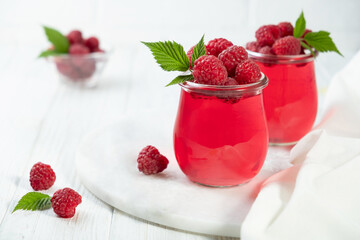 Sweet dessert jelly pudding with raspberries berries in glass jar on white background