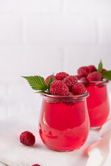 Sweet dessert jelly pudding with raspberries berries in glass jar on white background