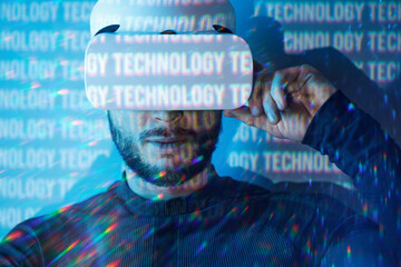 Young man in futuristic costume on blue neon light digital interface background. Guy using VR helmet. Augmented reality, virtual reality, future technology, game concept.