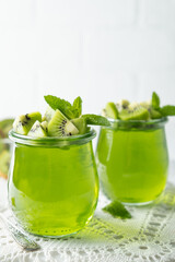 Sweet dessert jelly pudding with kiwi in glass jar on white background