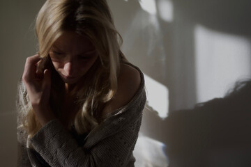 einsame Frau, nach unten blickend, traurige Stimmung, Schatten an der Wand