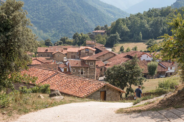 Brick houses in Mogrovejo in Cantabria, Spain with trees and mountains in the background