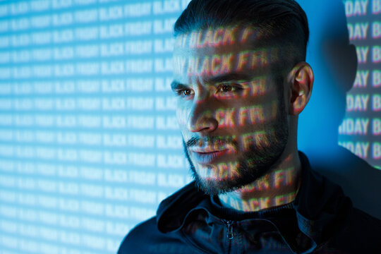 Young man with beard. Portrait of guy on blue neon light digital interface background. High fashion model posing in studio.