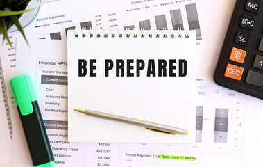 Notepad with text BE PREPARED on a white background, near marker, calculator.