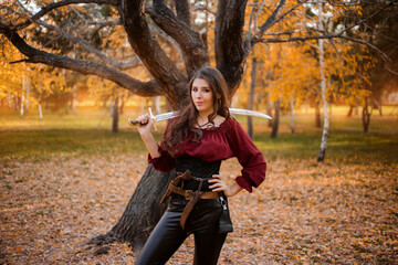 Portrait of an attractive slender woman with a saber on her shoulder against the background of an...