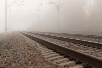 Fototapeta na wymiar Railroad tracks stretching into the misty distance. The path into fog and uncertainty.