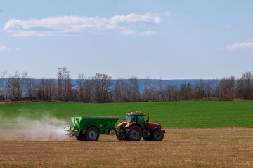 Fototapeta premium Tractor spreading fertilizer on grass field. Agricultural work.