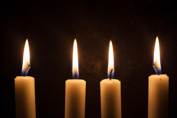 Four candles burning with black background
