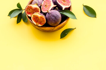 Fresh figs in a bowl with green leaves. Top view