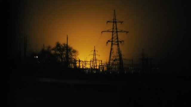 View from a car passing on the road at night on a power line against a background of an orange sky