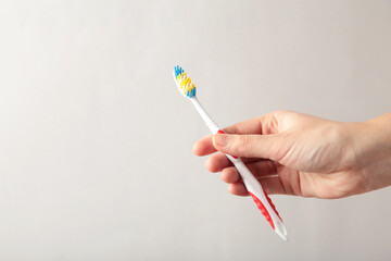 Toothbrush in woman's hand on grey background