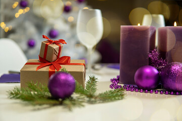 Christmas table decoration with gifts and purple candles.