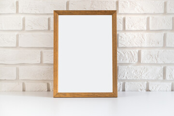 Blank wooden picture frame at the white brick wall with copy space