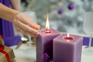 girl's hand lights candles on the christmas table