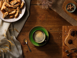 Americano Coffee Flat lay on an oak table with Italian Almond biscotti rough cut demerara sugar cubes whole arabica Coffee beans and organic ground coffee