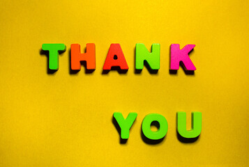 Word text Thank you inscription by wooden colorful crave letters at yellow craft paper with shadows, positivity, gratitude and kindness