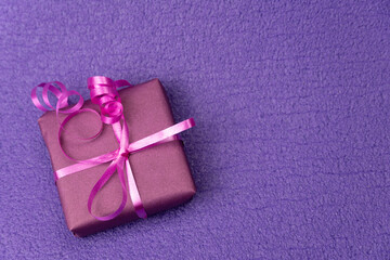 The box is wrapped in purple paper and tied with pink tape. .