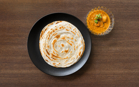South Indian Parota on a black plate, served with paneer curry for a quick meal.