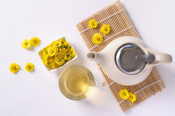 Organic Chrysanthemum flower tea in a cup and teapot on white background, Healthy Herbal drink, Top view