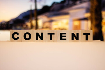 Cubes with the word - Content, against the background of real estate in the evening.