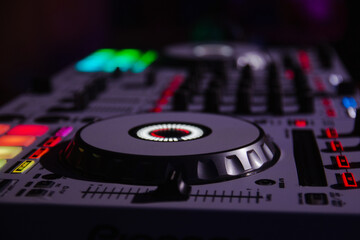 Closeup shot of a DJ turntable with various track controls in a night bar