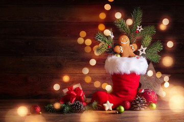 Nikolaus  -  Santa´s Boot -  Christmas decoration with gingerbread man on rustic wood background with fairy lights - 395754407