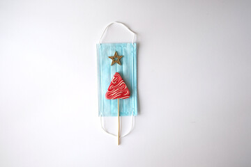 Flat lay. Christmas, new year and coronavirus theme. The medical mask, with a lollipop and an...