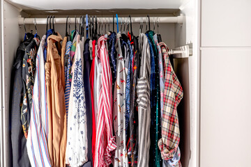Open wardrobe wardrobe with women's colored shirts