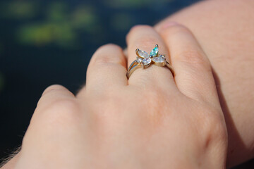 Female fingers with a beautiful ring with a flower-shaped ending with shimmering crystals.
