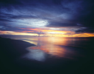 Fototapeta na wymiar Sunset and Overcast Sky Over Beach