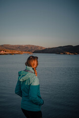 Fototapeta premium Young woman is enjoying beautiful view of sunset over norwegian fjord