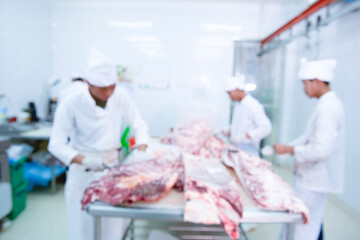 The image is blurry, a group of butchers working in slaughterhouses and cutting fresh Japanese wagyu beef for sale and processing.