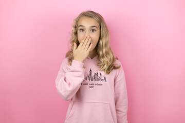 Young beautiful child girl standing over isolated pink background surprised covering her mouth
