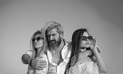 Young people friends of two pretty cute sexy girls or women and bearded man outdoors in park on...
