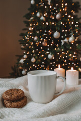 Cup with milk and cookies on the background of a beautiful Christmas tree and candles