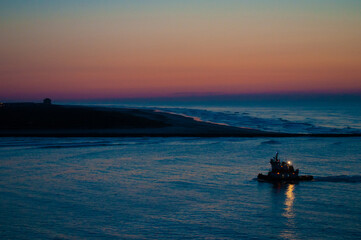 Naklejka na ściany i meble A fishing boat returns to the safety of Absecon Inlet in Atlantic City NJ after visiting the fishing ground in the Atlantic Ocean. Fishing boat launches after sunset to end it's the day!