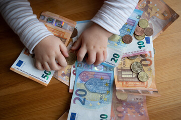 Kindergeld - Kind greift nach Bargeld