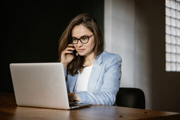 A woman at work does business on a laptop. Woman businessman working on laptop in office. Student in glasses to study on a laptop, vide connection.