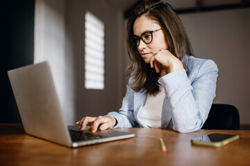 A woman at work does business on a laptop. Woman businessman working on laptop in office. Student in glasses to study on a laptop, vide connection.