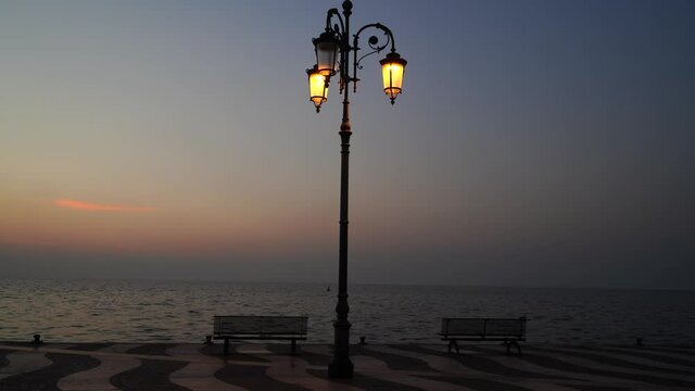 Retro street light and two benches in Lazise at the Garda Lake promenade, province Verona, in the late afternoon in November, 2020.