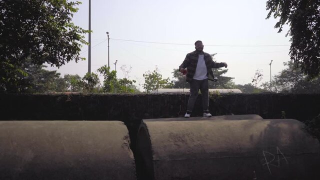 boy gangster looking man dancing on sewage pipe India Mumbai gimble shot