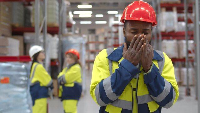 Young african manager coughing and feeling sick in warehouse