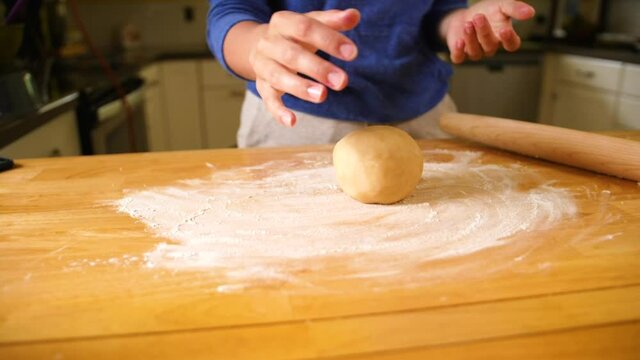 hands flattening dough ball out to bake a pie crust.