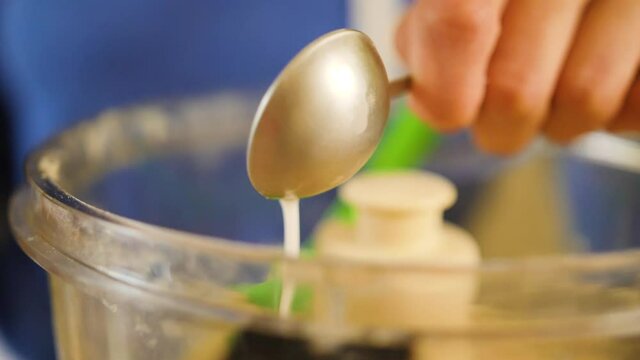 pouring milk from tablespoon into food processor baking a pie