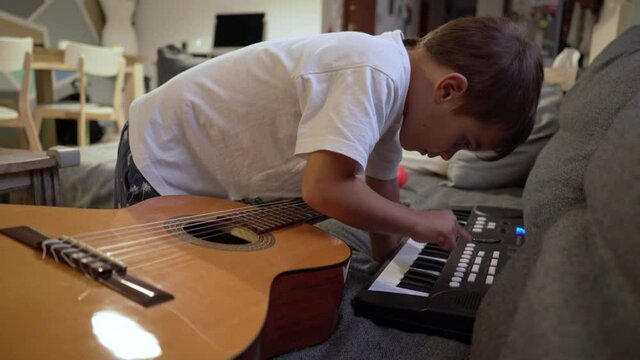 Caucasian boy toddler, plays with music instruments at home, during coronavirus lockdown, 4K medium shot