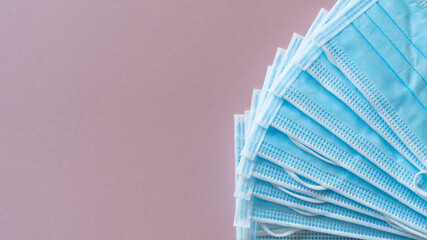 Pack of surgical pandemic masks fanned out on a pink background