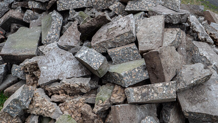 Pieces of broken gray concrete lying on the grass