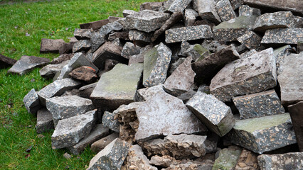 Pieces of broken gray concrete lying on the grass