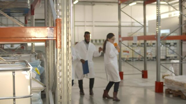 Multiethnic warehouse workers team in white coats smiling and dancing