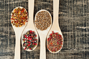 A mixture of various spices in a wooden spoon. Spices and seasonings on an old shabby board. Mix on a pile close up. Place for text and copy space near the spoon.